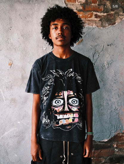 Model wearing the Pushin Flowers Crash Out tee in Acid Washed Black, front view showing the distressed chest graphic