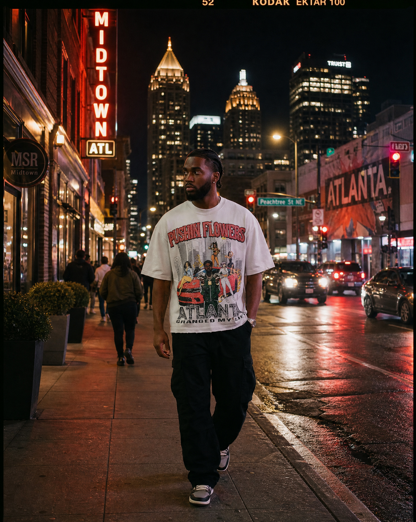 Model wearing Pushin Flowers Atlanta graphic t-shirt on a downtown Atlanta street at night